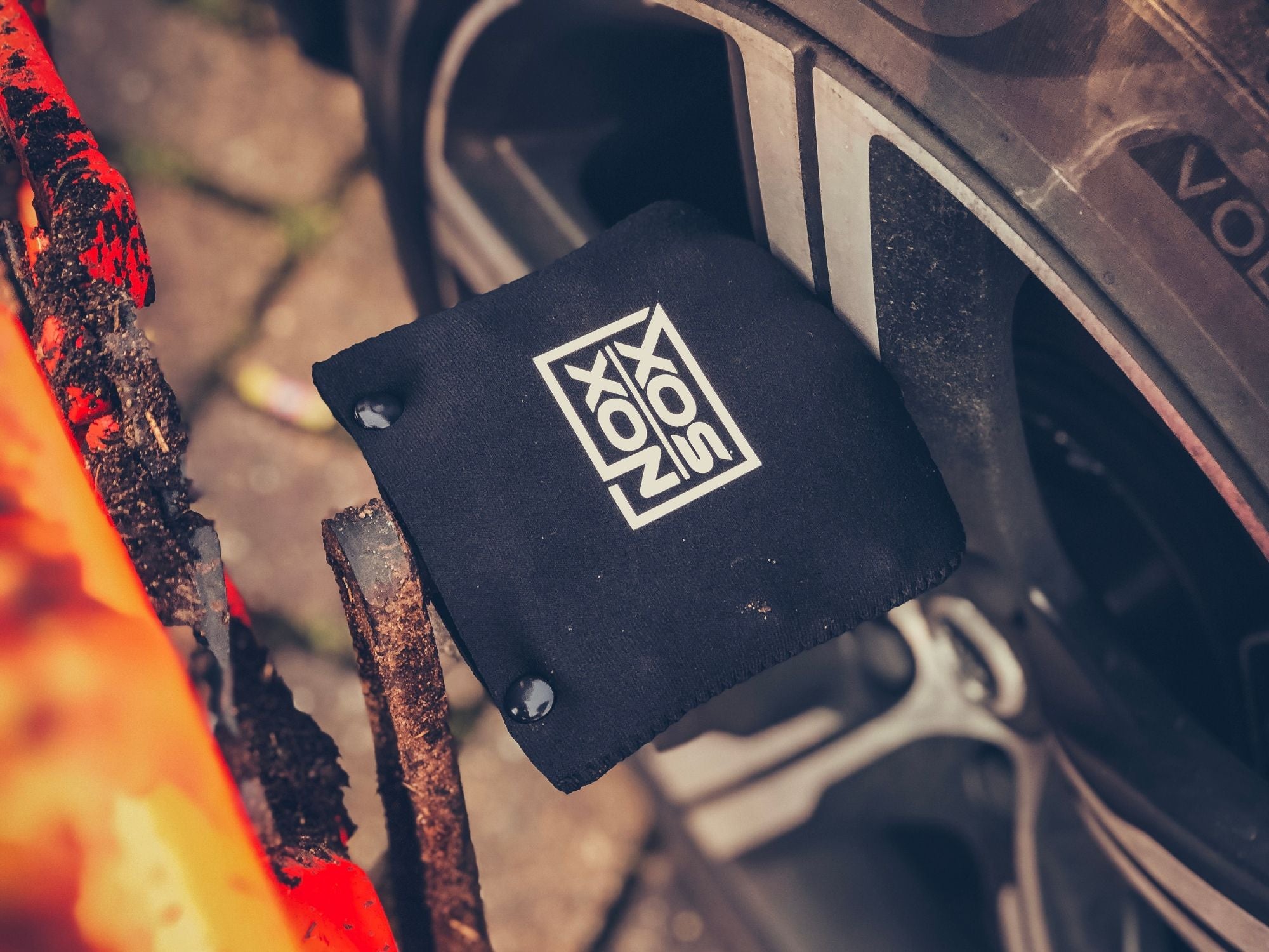 Nox Sox covered pedal leaning against a car wheel.